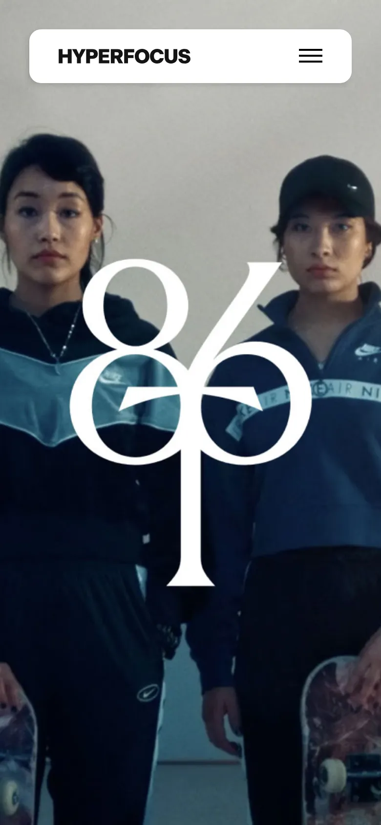 The mobile version simplifies the navigation into a white header containing the Hyperfocus logo and a hamburger menu icon on the right. The hero section features a full-width, high-impact photograph of two people wearing athletic gear, with a large, stylized white graphic overlaid in the center. The layout shifts from a wide horizontal orientation to a vertical, image-focused stack.