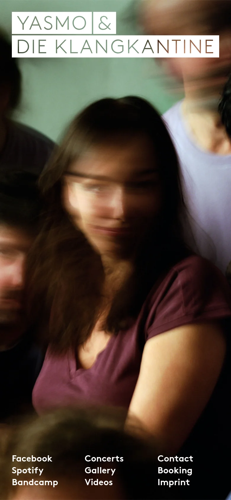 The mobile version maintains the motion-blurred band photo as a full-screen background with the white logo at the top. The navigation links are rearranged into a compact three-column grid at the bottom of the screen for easier vertical scrolling. The layout is simplified to fit the narrow portrait orientation.
