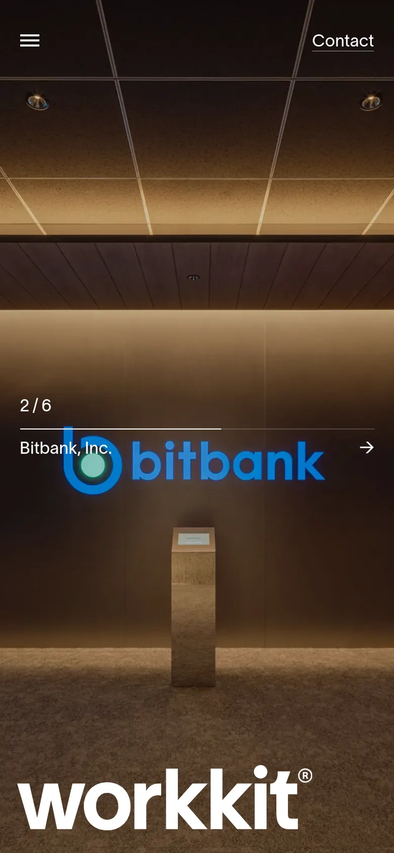 The mobile version uses a vertical layout with a simplified header containing a hamburger menu and a 'Contact' link. The hero section displays a large image of an office interior with the 'workkit' logo at the bottom and a '2/6 Bitbank, Inc.' indicator with a directional arrow.