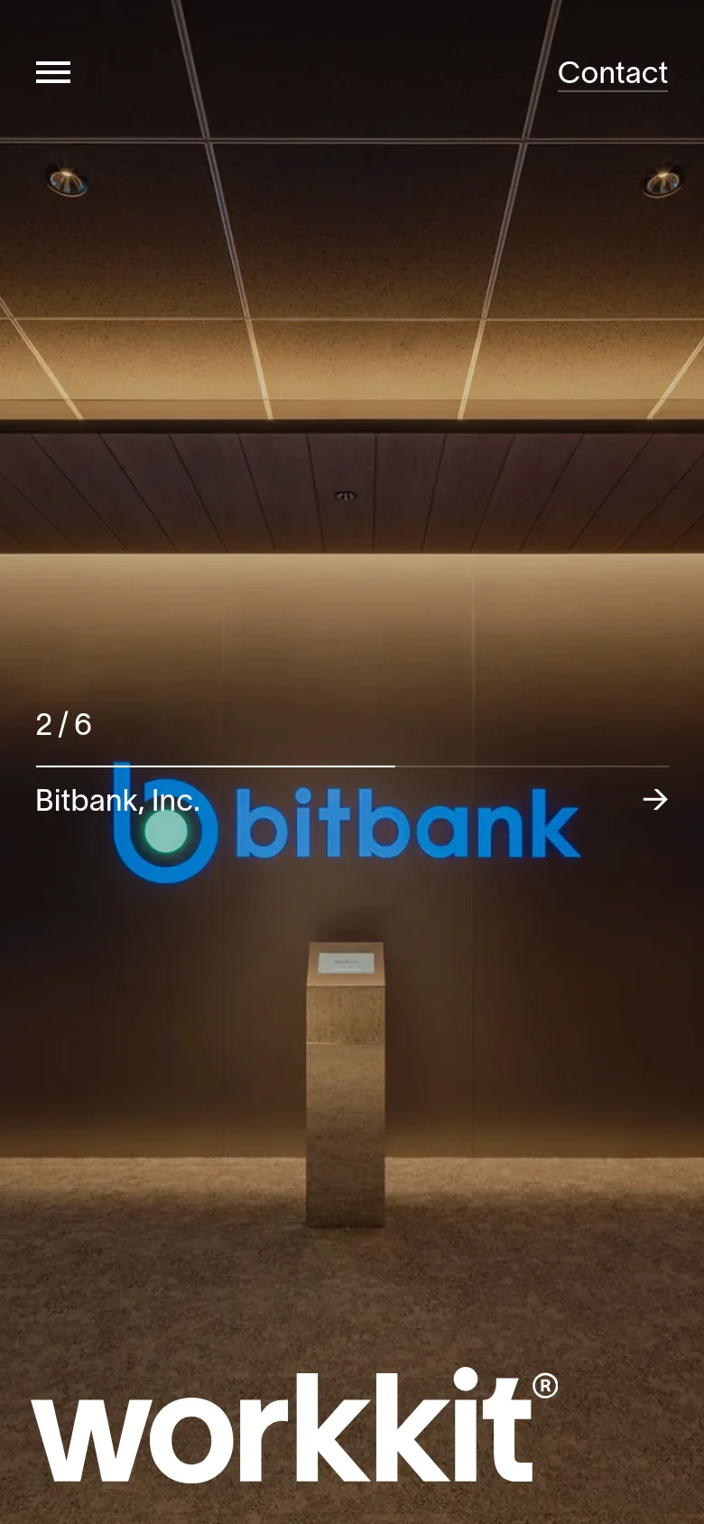 The mobile version uses a vertical layout with a simplified header containing a hamburger menu and a 'Contact' link. The hero section displays a large image of an office interior with the 'workkit' logo at the bottom and a '2/6 Bitbank, Inc.' indicator with a directional arrow.
