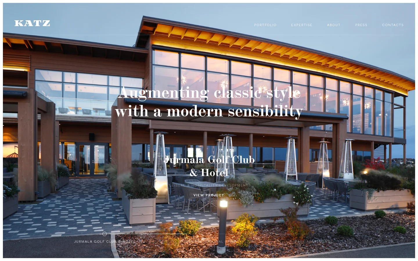 The desktop homepage features a large hero image of a modern wooden building with glowing windows at dusk, overlaid with the headline 'Augmenting classic style with a modern sensibility'. A navigation menu with links for Portfolio, Expertise, About, Press, and Contacts is at the top right, and the Katz logo is at the top left. Below the hero section, a grid displays featured projects like Jurmala Golf Club & Hotel with 'View project' calls to action.