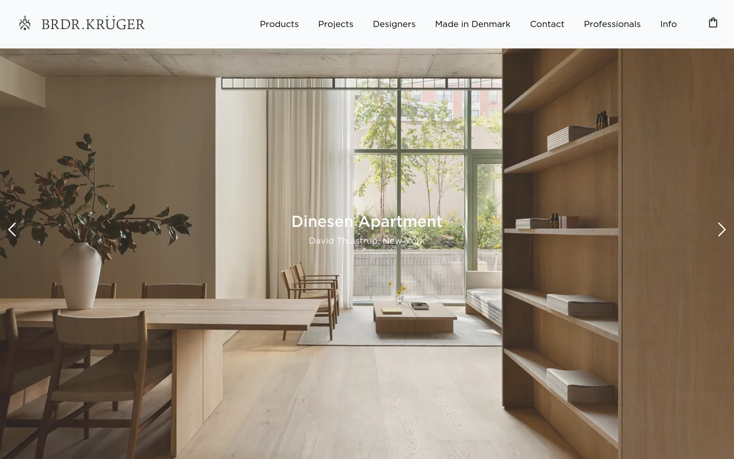 The desktop homepage features a minimalist design with a large hero image of a bright, modern living space titled 'Dinesen Apartment' by David Thulstrup. A clean navigation menu at the top includes links for Products, Projects, Designers, and more, set against a white background. Large directional arrows on the sides of the hero image indicate a slideshow format.