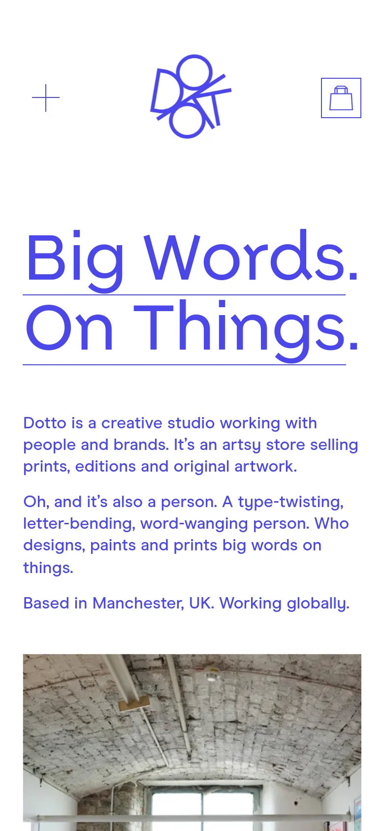 The mobile version uses a centered layout with a large blue logo at the top and a shopping bag icon. The headline 'Big Words. On Things.' is prominently displayed in large blue text, followed by the studio's descriptive text below it. The navigation menu is condensed, and the content stacks vertically for easier scrolling.