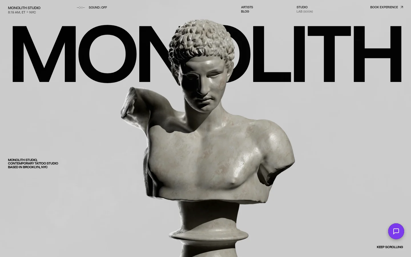 The desktop homepage features a minimalist design with a large, central hero image of a classical marble bust against a light gray background. The word 'MONOLITH' is displayed in massive black typography behind the statue, with a navigation menu at the top containing links for Artists, Studio, Blog, and Book Experience. A small purple chat icon sits in the bottom right corner.