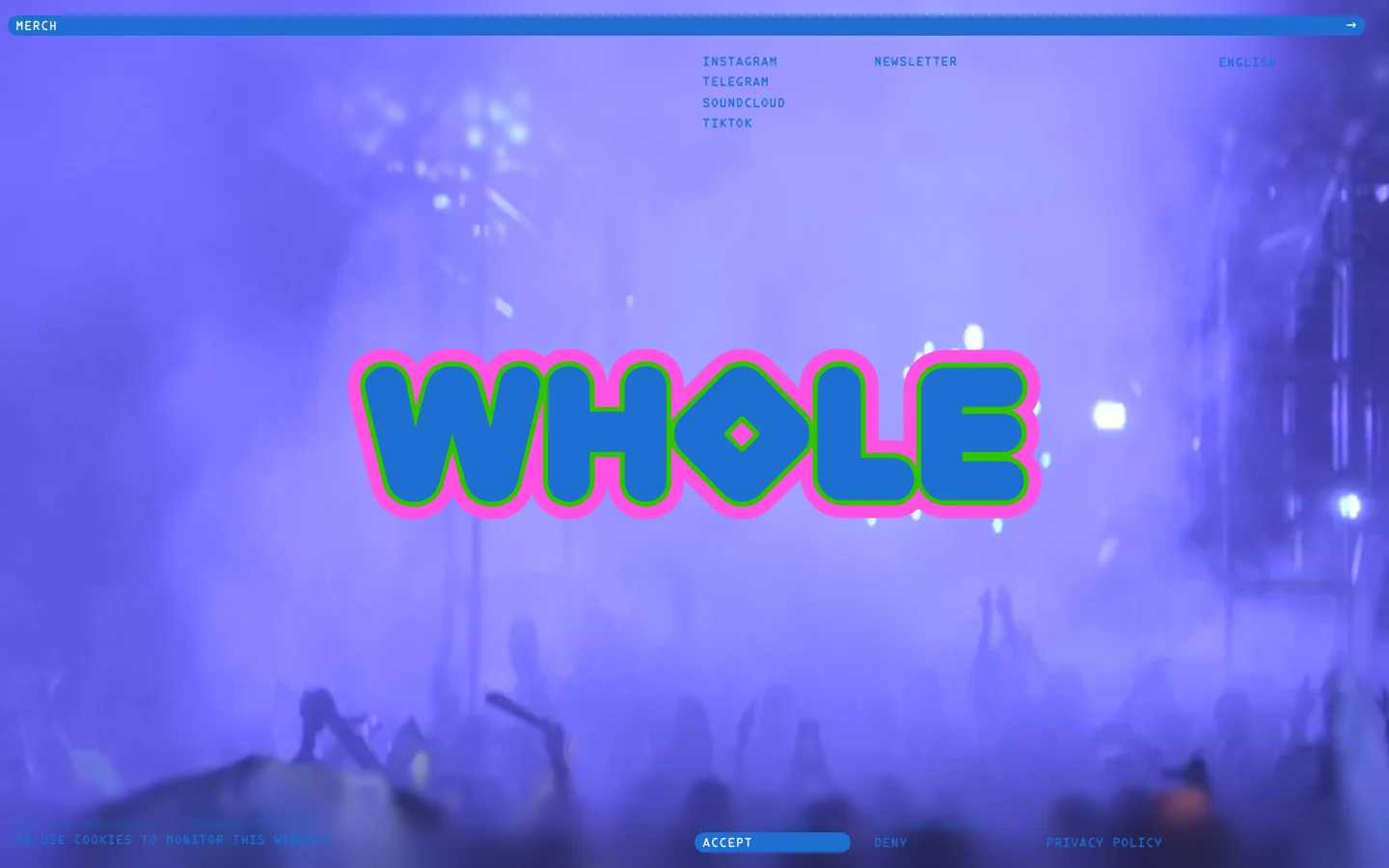 The desktop homepage features a large, stylized 'WHOLE' logo in teal with a pink outline centered over a purple-tinted, atmospheric photo of a festival crowd. A blue navigation bar at the top contains a 'MERCH' link, while social media links and a newsletter signup are positioned in the upper right. The overall color palette is dominated by vibrant purples, blues, and pinks.