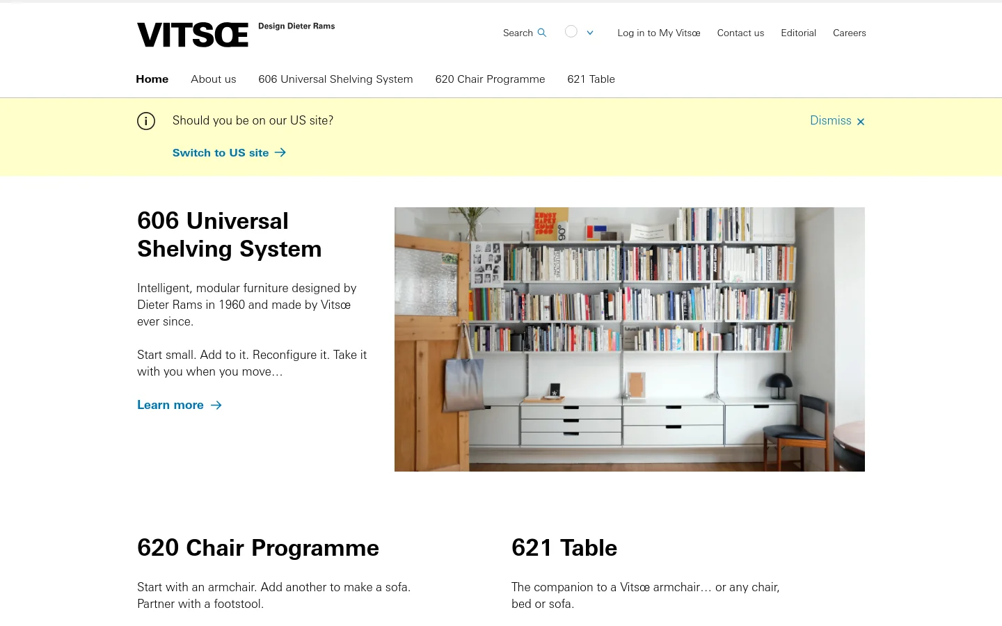 The Vitsœ homepage features a minimalist design with a white background and black typography. A large hero image showcases the 606 Universal Shelving System filled with books, followed by sections for the 620 Chair Programme and 621 Table, each with descriptive text and 'Learn more' links. A yellow notification banner at the top suggests switching to the US site.