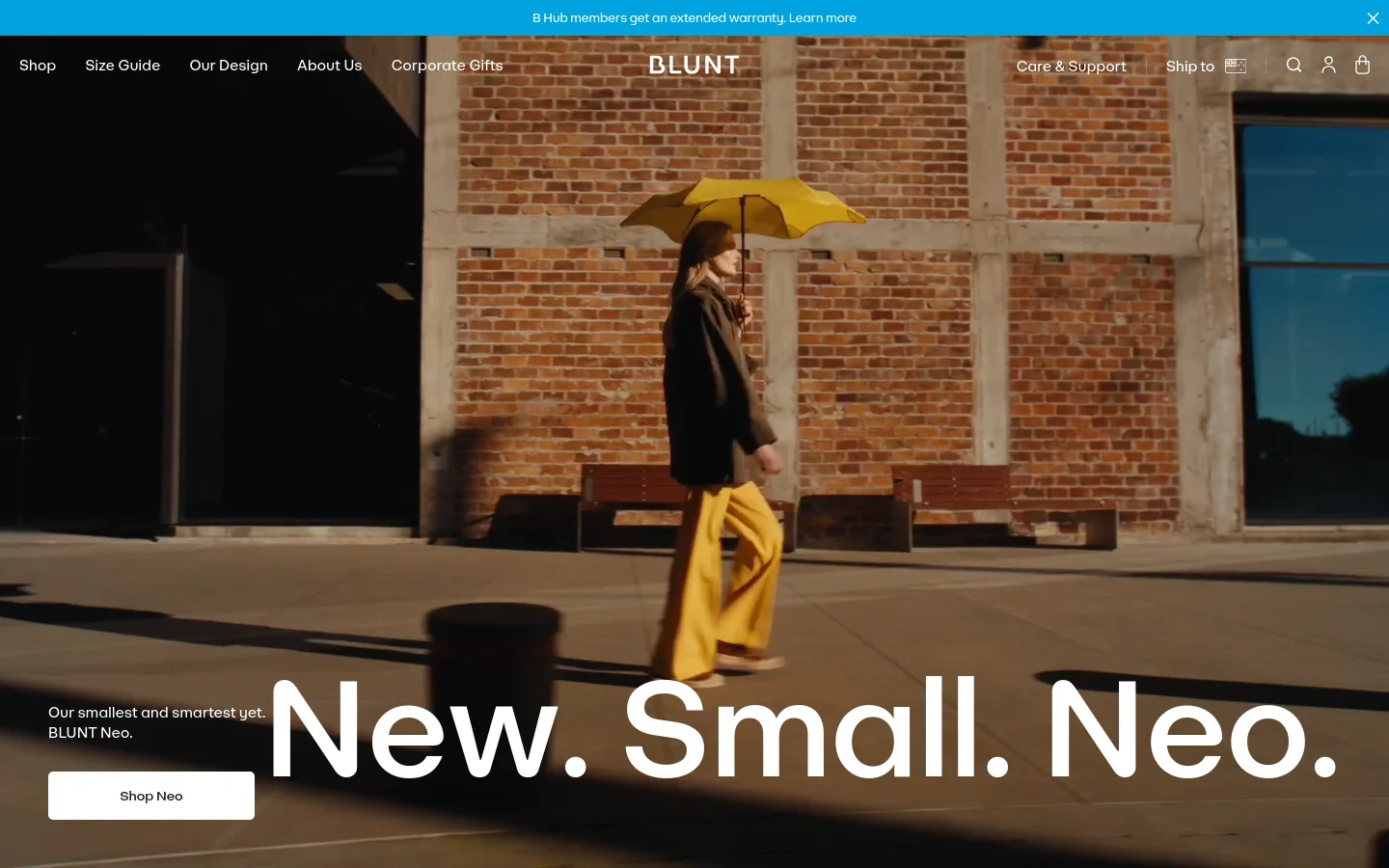 The desktop homepage features a large hero image of a person walking with a yellow umbrella against a brick building. A prominent white headline reads 'New. Small. Neo.' with a 'Shop Neo' call-to-action button, all set against a warm, urban background. The navigation menu is spread across the top with links for Shop, Size Guide, and Our Design.