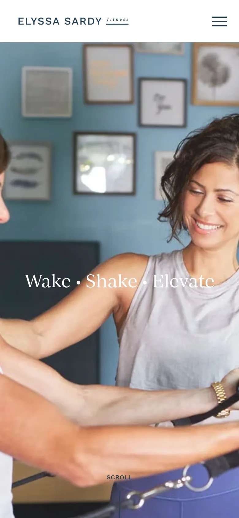 The mobile version shows a vertically oriented, zoomed-in view of the hero image featuring the two women and the 'Wake • Shake • Elevate' headline. The layout is simplified for a smaller screen, maintaining the logo at the top and the 'SCROLL' prompt at the bottom against the studio background.