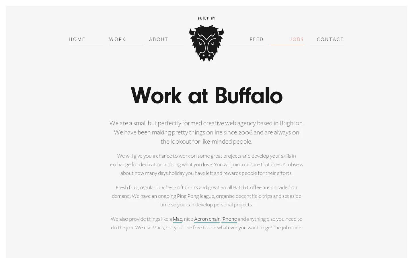 The desktop page features a minimalist design with a light grey background and a centered black buffalo logo in the navigation bar. The main headline reads 'Work at Buffalo' in large, bold black text, followed by several paragraphs of centered grey text describing the agency's culture and perks. The navigation menu includes links for Home, Work, About, Feed, Jobs, and Contact, with 'Jobs' underlined in pink.