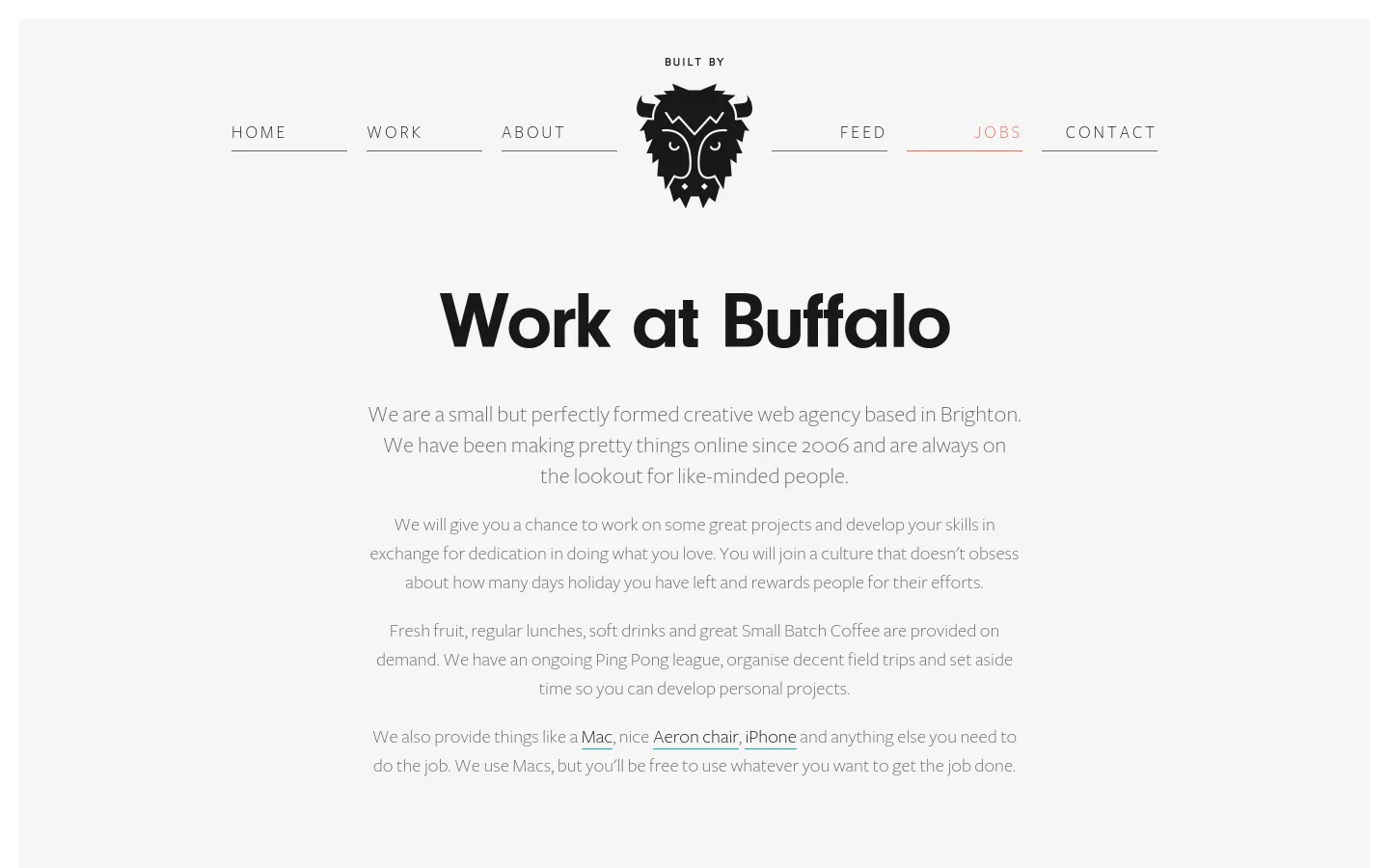 The desktop page features a minimalist design with a light grey background and a centered black buffalo logo in the navigation bar. The main headline reads 'Work at Buffalo' in large, bold black text, followed by several paragraphs of centered grey text describing the agency's culture and perks. The navigation menu includes links for Home, Work, About, Feed, Jobs, and Contact, with 'Jobs' underlined in pink.