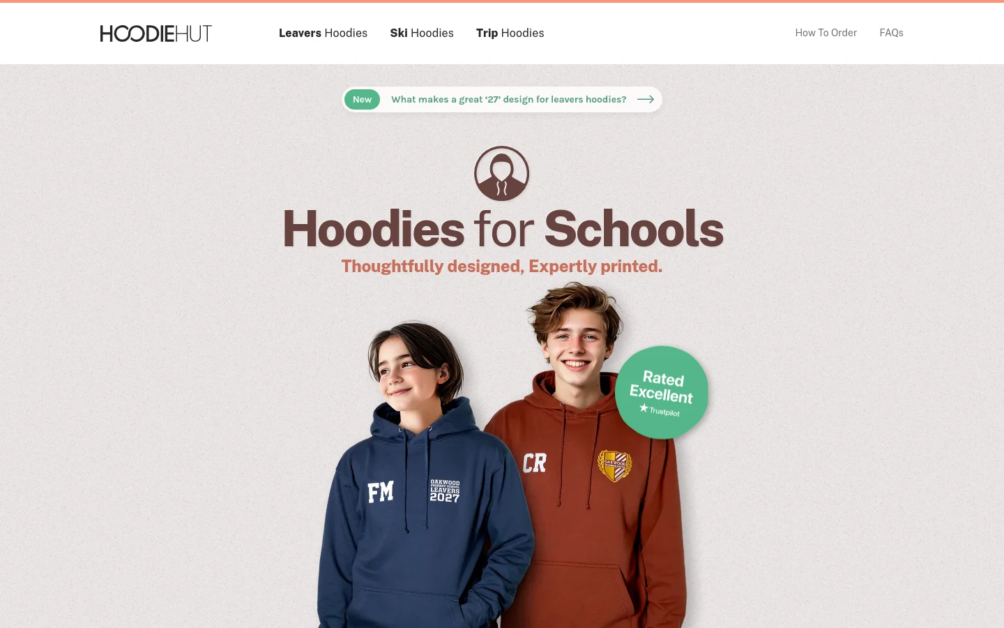 The desktop homepage features a clean, light-textured background with a navigation bar containing links for Leavers Hoodies, Ski Hoodies, and Trip Hoodies. The hero section displays the headline 'Hoodies for Schools' above a large image of two smiling students wearing navy and rust-colored personalized hoodies, accompanied by a green 'Rated Excellent' Trustpilot badge.