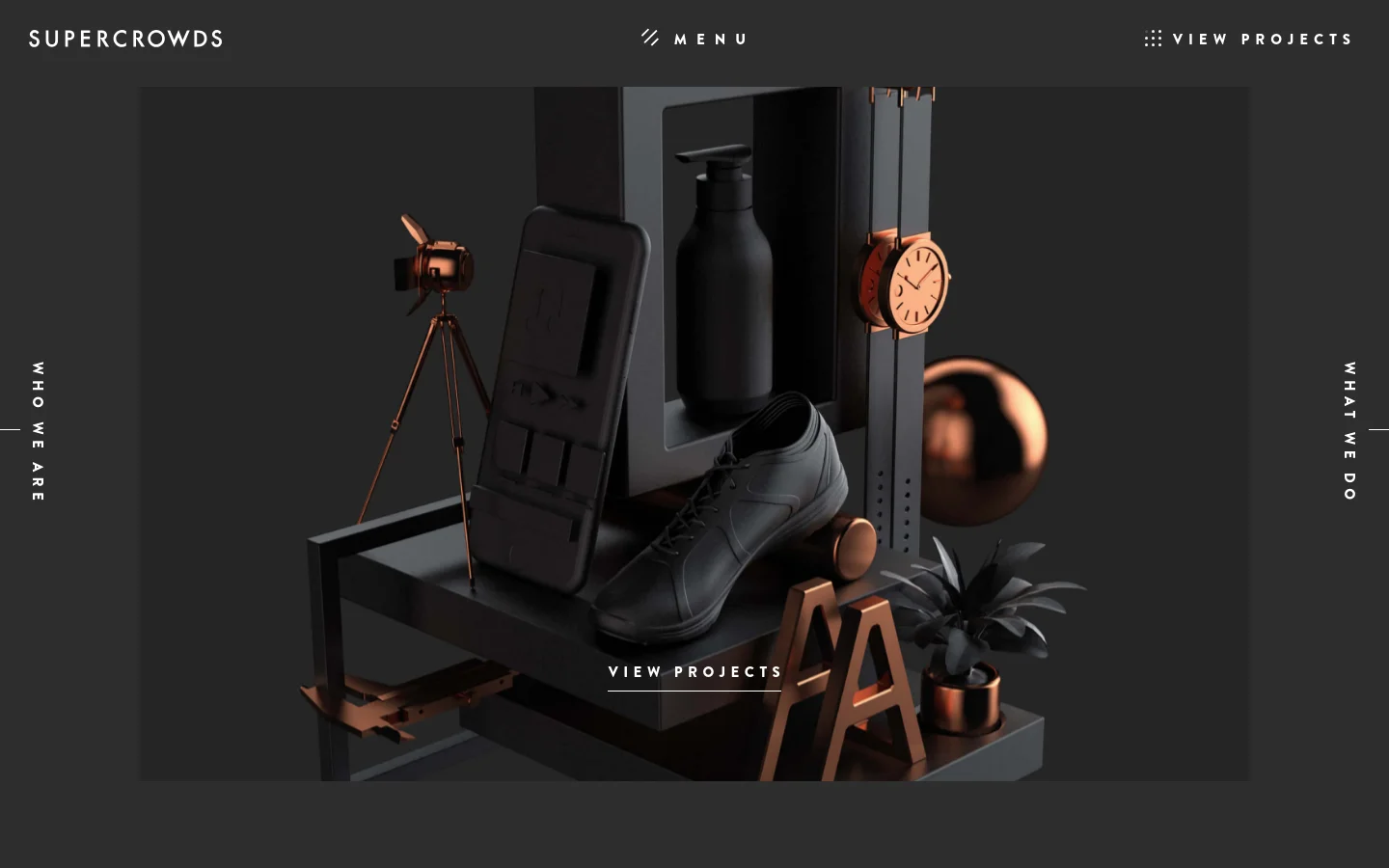 The desktop homepage features a dark, minimalist aesthetic with a large hero image of a stylized 3D arrangement of objects including a shoe, a watch, and a camera. Navigation links for 'MENU', 'VIEW PROJECTS', 'WHO WE ARE', and 'WHAT WE DO' are spaced around the edges of the screen in white sans-serif typography.