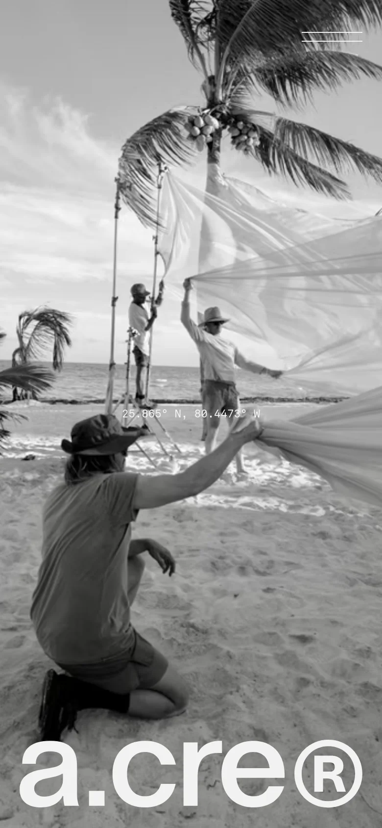 The mobile version maintains the dark, minimalist theme but presents the content in a vertical orientation. The black and white hero image of a beach film production is scaled to fit the narrow screen, with the 'a.cre®' logo positioned at the bottom and minimal white text elements appearing at the top and center.