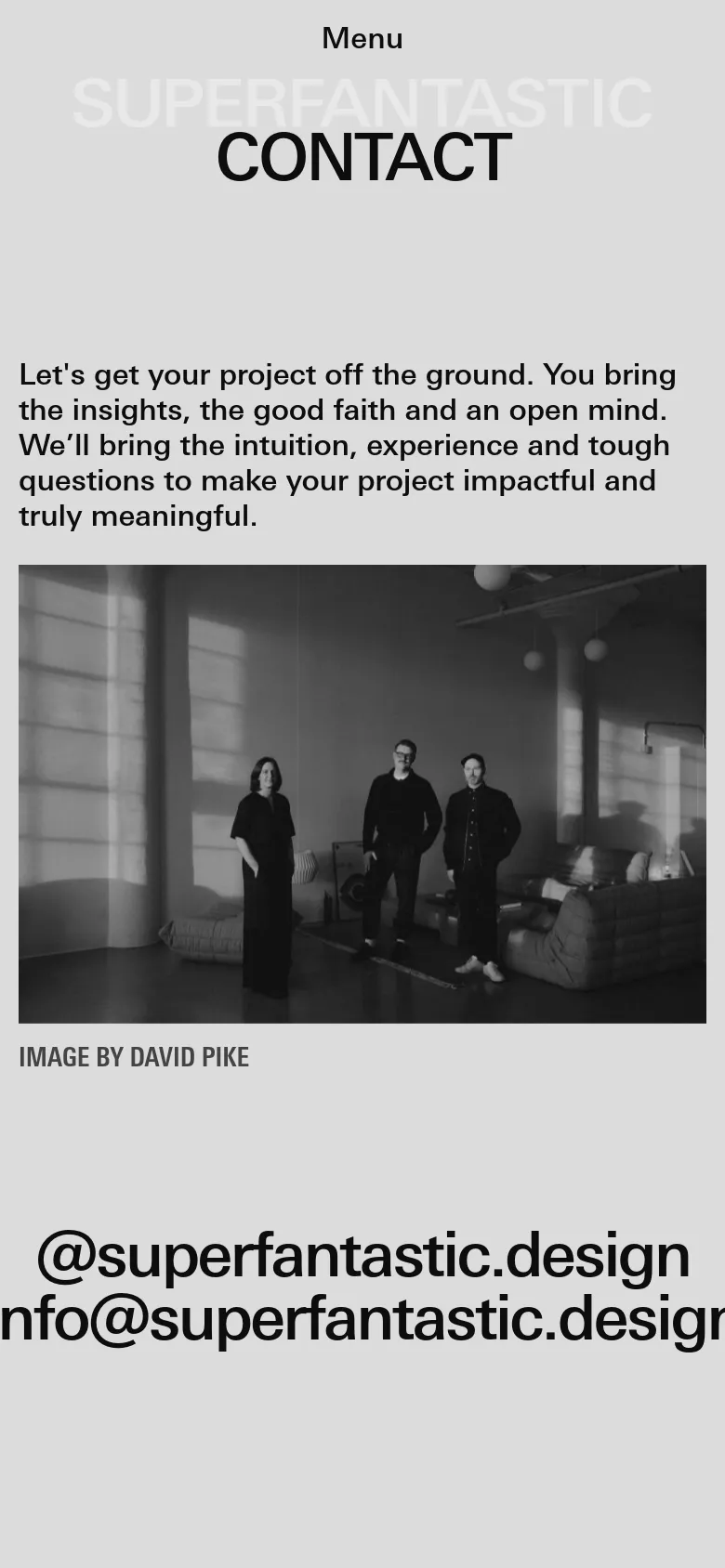 The mobile version maintains the minimalist light gray theme and bold black typography but stacks the content vertically. The large 'CONTACT' headline and mission statement appear first, followed by the black-and-white hero image which spans the width of the screen. The top navigation is condensed into a 'Menu' label to accommodate the smaller viewport.