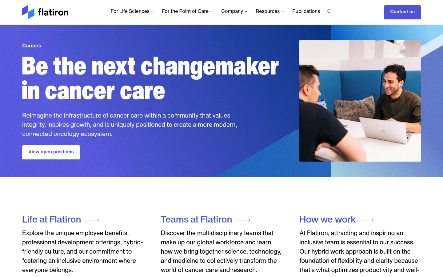 The desktop Careers page features a large blue hero section with the headline 'Be the next changemaker in cancer care' and a white 'View open positions' button. To the right is a photograph of two colleagues working together on a laptop in a modern office. Below the hero, three columns with headings 'Life at Flatiron', 'Teams at Flatiron', and 'How we work' provide links to more information.