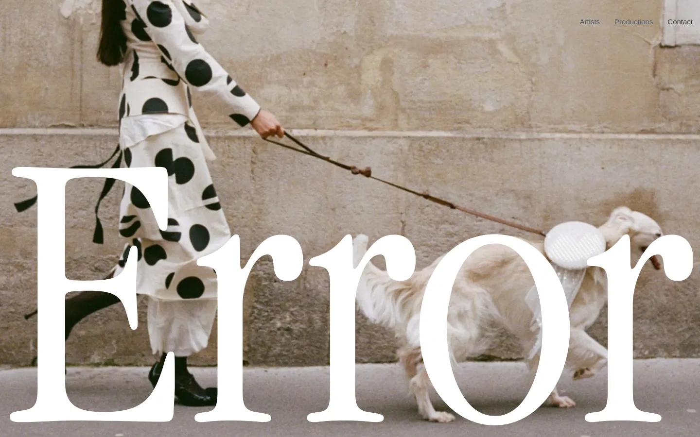 The desktop homepage features a large hero image of a person in a polka-dot dress walking a white dog, with the word 'Error' in large white serif typography overlaid in the foreground. A minimalist navigation menu with links for Artists, Productions, and Contact is located in the top right corner against a neutral, textured wall background.