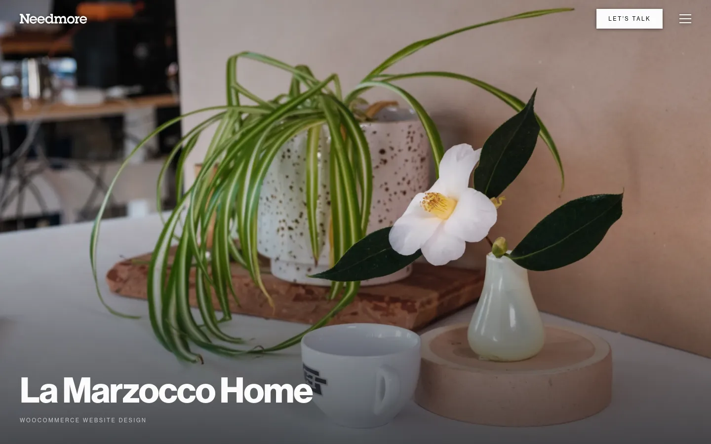 A portfolio page for La Marzocco Home featuring a large lifestyle hero image of a white flower and a spider plant in a speckled pot next to a coffee cup. The layout includes a dark overlay at the bottom with the headline 'La Marzocco Home' and a 'WooCommerce website design' subheadline. A navigation bar at the top contains the Needmore logo, a 'LET'S TALK' call to action button, and a hamburger menu icon.