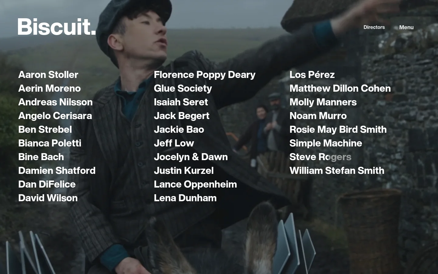 The desktop homepage features a large, cinematic background image of a man in a dark coat outdoors. The 'Biscuit.' logo is in the top left, with 'Directors' and 'Menu' links in the top right. A three-column list of director names is overlaid on the bottom half of the image in white text.