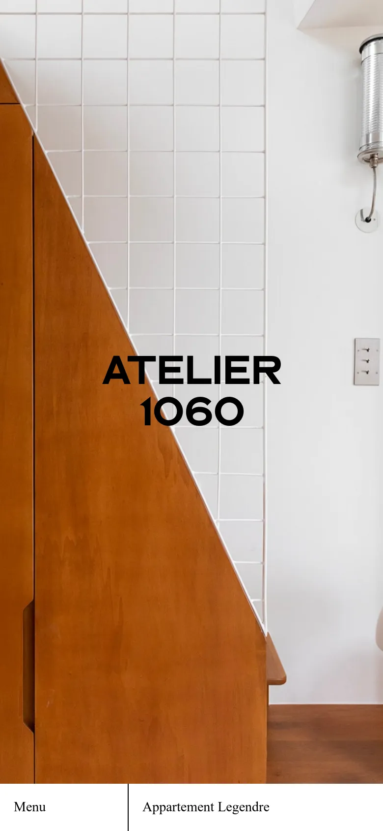The mobile version presents a simplified, vertically stacked view of the homepage. The hero image is tightly cropped on the wooden cabinetry and white tiles, with the 'ATELIER 1060' headline prominently centered. Navigation is condensed into a bottom bar featuring a 'Menu' button and the 'Appartement Legendre' link.