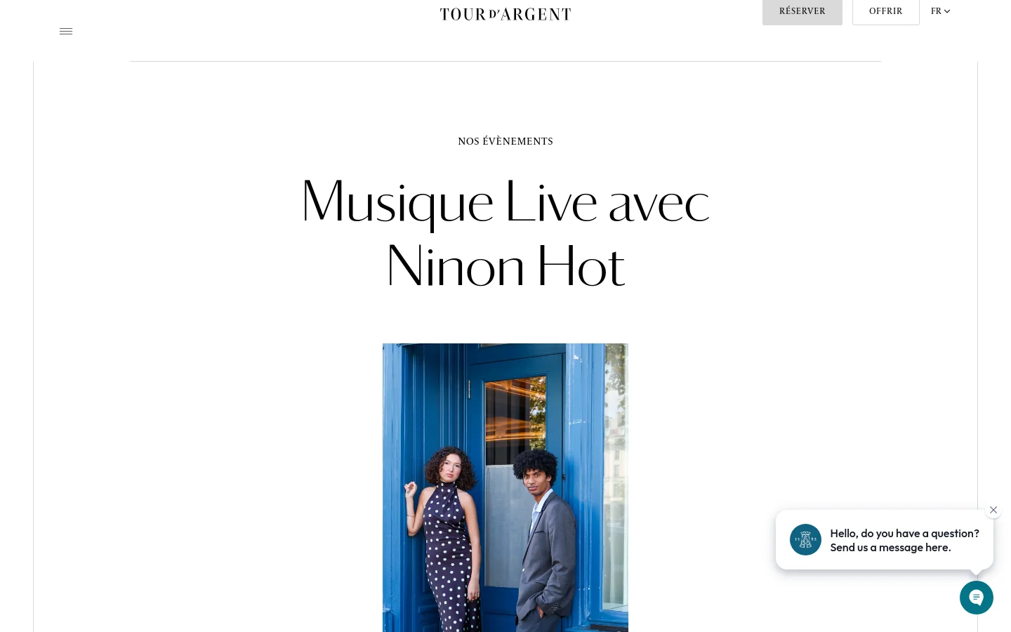 The desktop page features a minimalist white background with the headline 'NOS ÉVÈNEMENTS' and a large, elegant serif title 'Musique Live avec Ninon Hot'. Below the text, a vertical portrait shows two people posing in front of a bright blue door, with a floating chat widget in the bottom right corner.