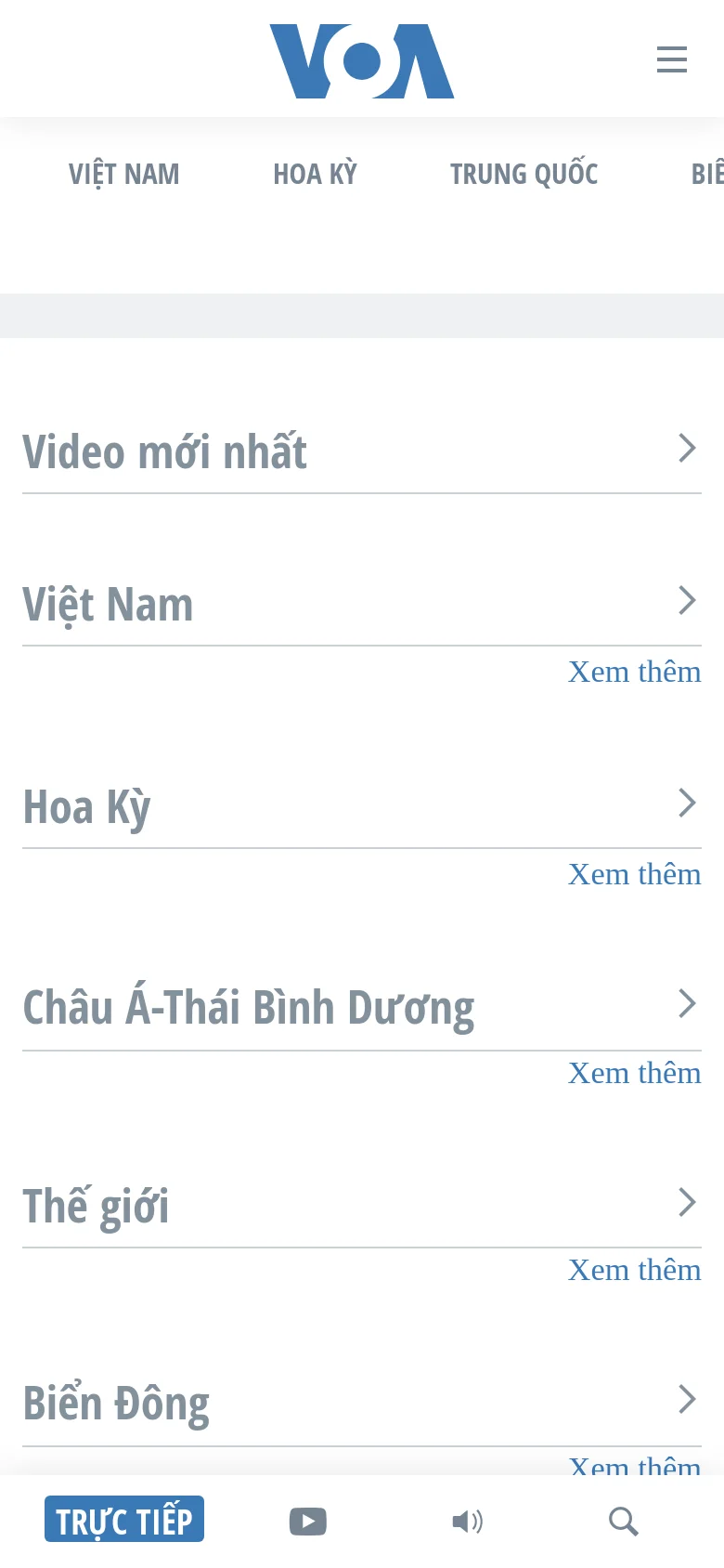 The mobile version presents a simplified, vertical layout optimized for scrolling. The VOA logo is centered at the top above a hamburger menu icon, and news categories like 'Video mới nhất' and 'Việt Nam' are stacked vertically as full-width list items with chevron icons. A fixed bottom navigation bar provides quick access to live video, YouTube, audio, and search functions.
