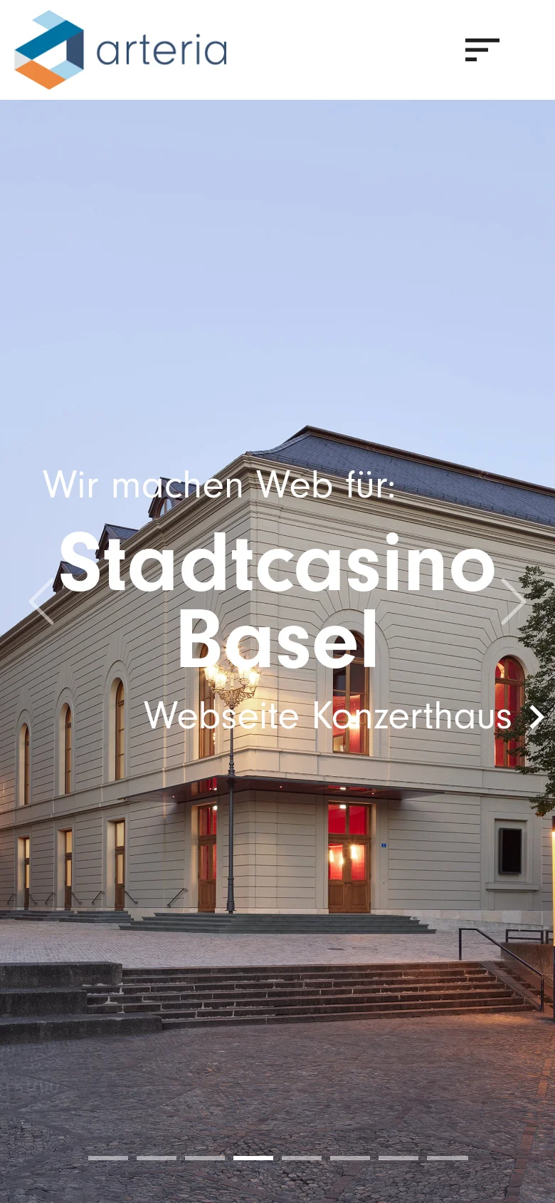 The mobile version displays a full-width hero image of the Stadtcasino Basel building at dusk. Large white text overlays the image reading 'Wir machen Web für: Stadtcasino Basel' and 'Webseite Konzerthaus'. The layout is vertically oriented with a simplified header containing the logo and a menu icon, and navigation dots at the bottom of the hero section.