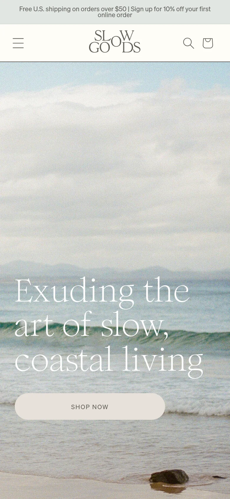 The mobile version presents a vertically oriented view of the coastal hero image, with the headline and 'SHOP NOW' button centered in the lower half of the screen. The navigation is condensed into a hamburger menu icon on the top left, with a search icon and shopping bag icon on the top right, maintaining the same soft, coastal aesthetic.