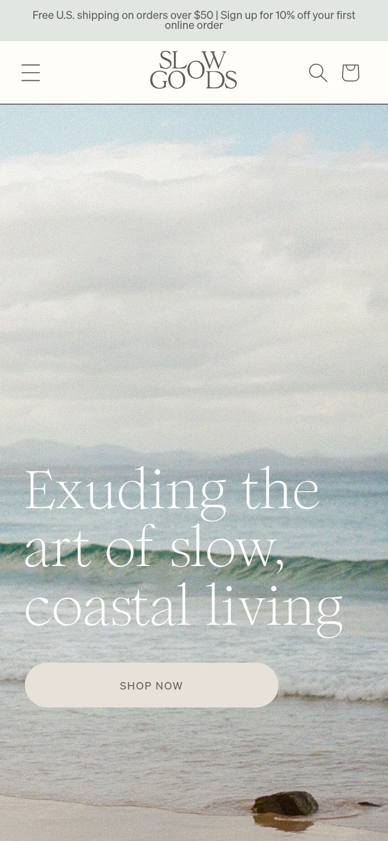 The mobile version presents a vertically oriented view of the coastal hero image, with the headline and 'SHOP NOW' button centered in the lower half of the screen. The navigation is condensed into a hamburger menu icon on the top left, with a search icon and shopping bag icon on the top right, maintaining the same soft, coastal aesthetic.