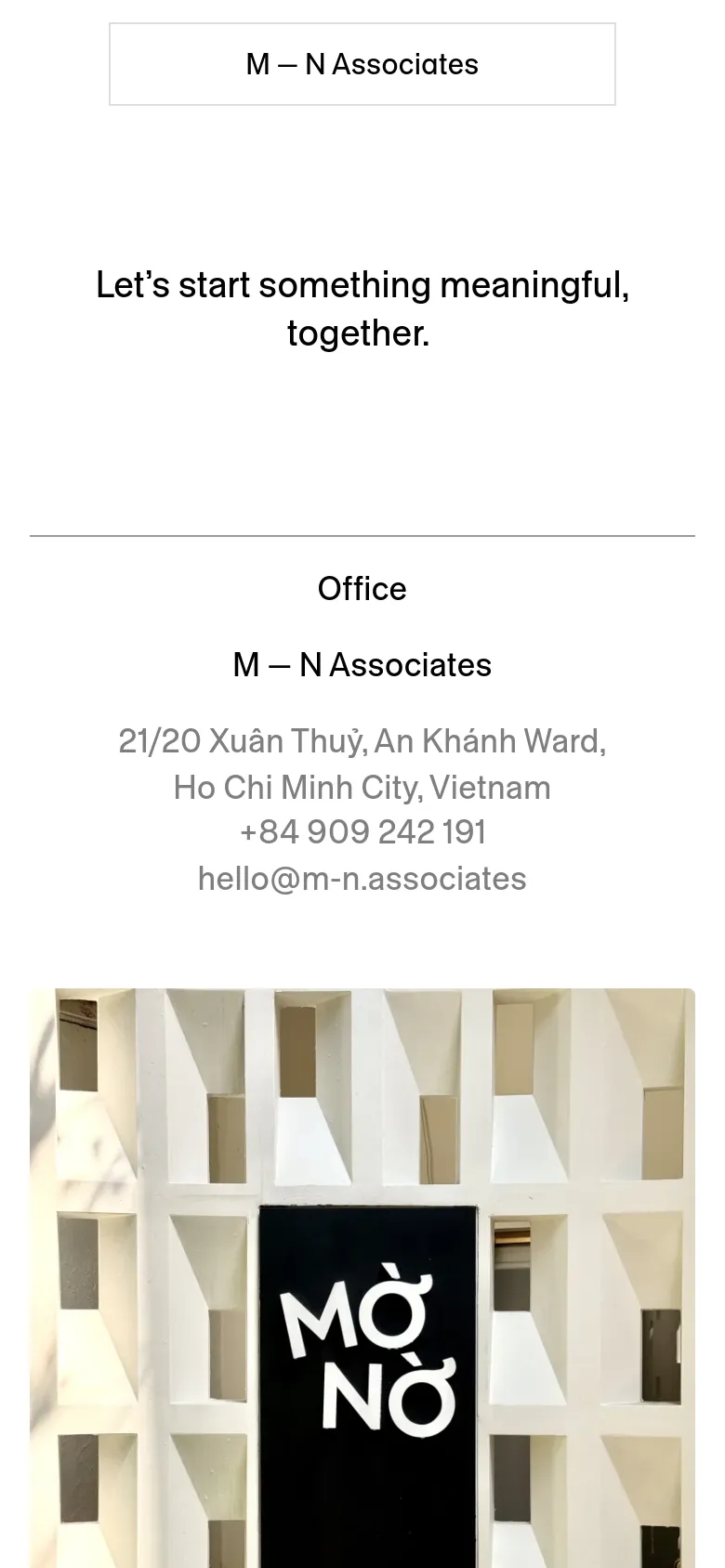 The mobile version maintains the minimalist white and black aesthetic but stacks elements vertically for a narrower viewport. The headline, contact information, and large architectural image are centered in a single column, ensuring readability on a smaller screen.