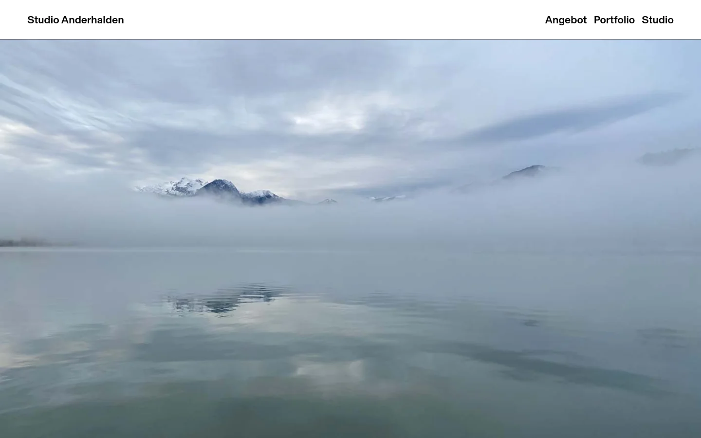 The desktop homepage features a minimalist white header with the title 'Studio Anderhalden' on the left and navigation links 'Angebot', 'Portfolio', and 'Studio' on the right. Below the header, a large hero image shows a serene, misty landscape of mountains reflecting in calm water under a cloudy sky. A large black headline below the image reads, 'Vieles wächst in der Ruhe. Wenn das Unnötige geht, bleibt Klarheit.'