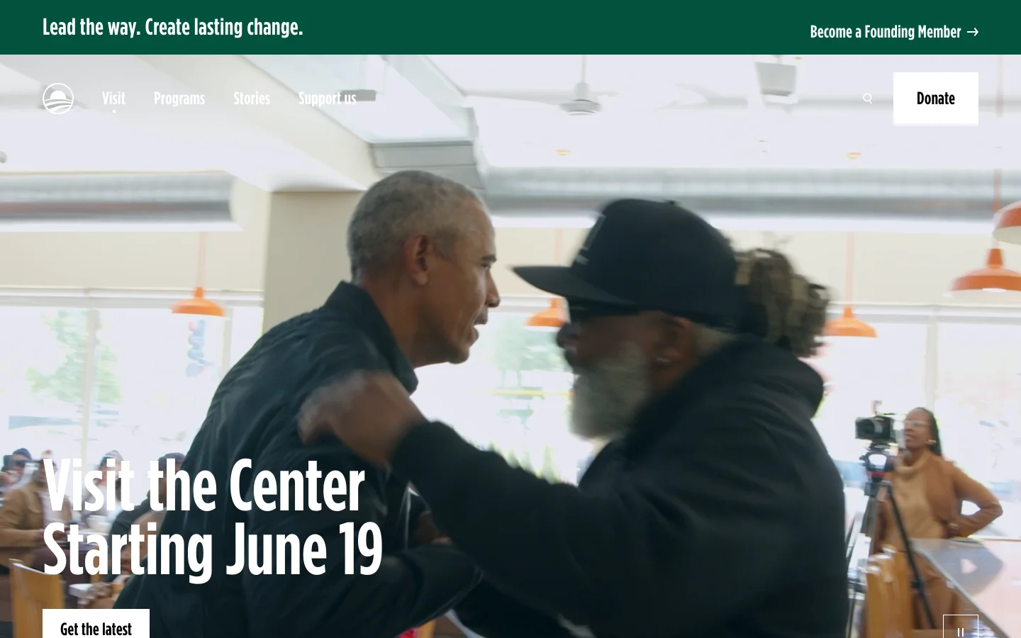 The desktop page features a large hero video background showing Barack Obama interacting with others, overlaid with the headline 'Visit the Center Starting June 19' and a 'Get the latest' button. A white navigation bar at the top includes links for Visit, Programs, Stories, and Support Us, alongside a search icon and a prominent 'Donate' button. The layout is clean with high-contrast white text over a dark, cinematic video background.