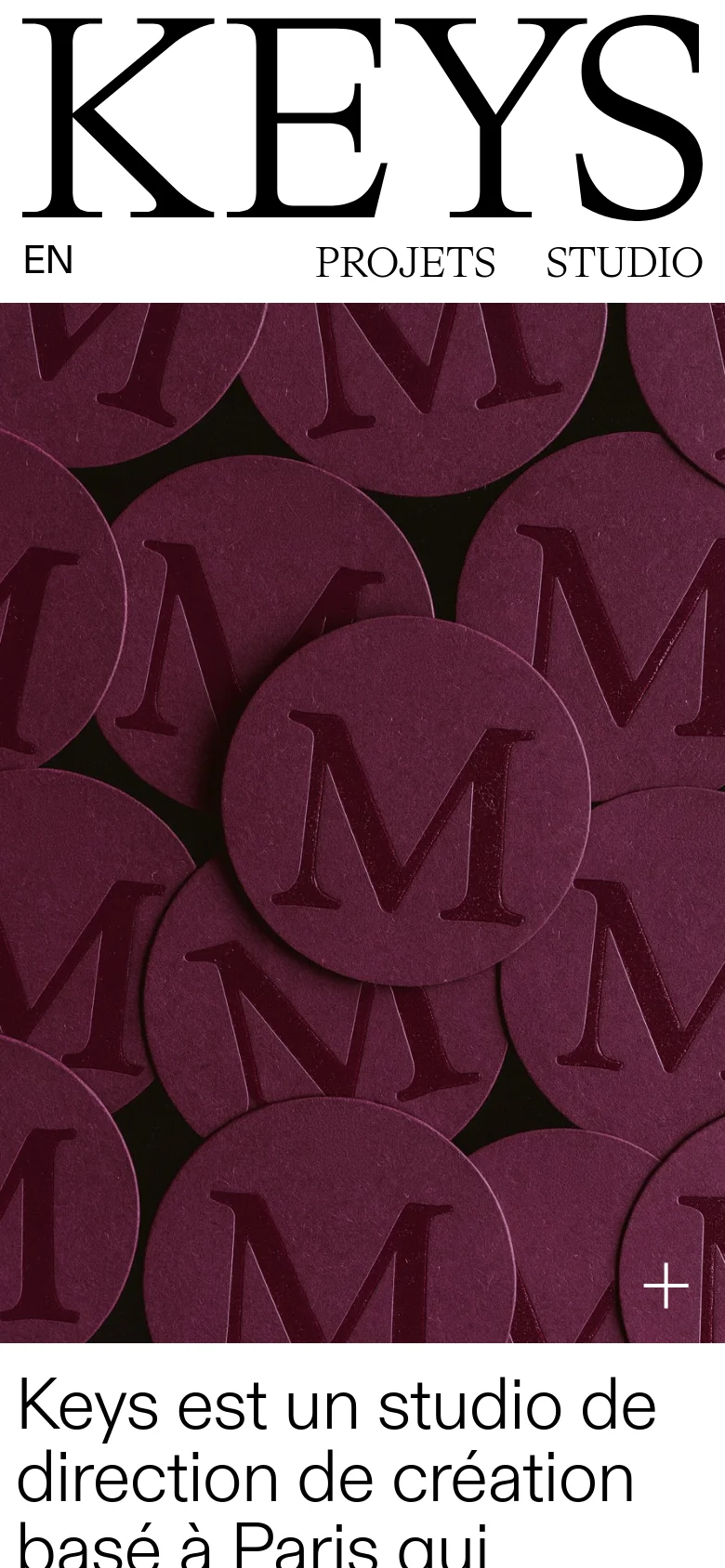 The mobile version presents a vertically stacked layout, starting with a large brand logo 'KEYS' and navigation links 'EN', 'PROJETS', and 'STUDIO'. The hero image shows a close-up of dark maroon circular textured elements with the letter 'M' embossed on them. A large text block follows, describing the creative direction studio in a clean, black serif font on a white background.