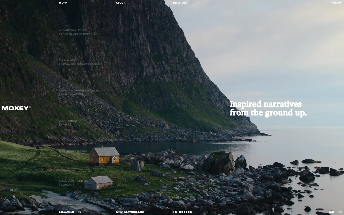 The desktop homepage features a cinematic full-screen background image of a rocky coastline with a small yellow house. A large headline reads 'Inspired narratives from the ground up.' Navigation links for Work, About, and Let's Talk are at the top, while a list of video project titles is overlaid on the left side of the landscape.