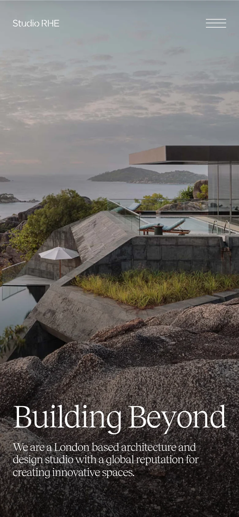 The mobile version maintains the large hero image of the coastal residence but scales the layout vertically. The 'Building Beyond' headline and mission statement are repositioned to the bottom of the screen, and the navigation menu is condensed into a hamburger icon on the right.