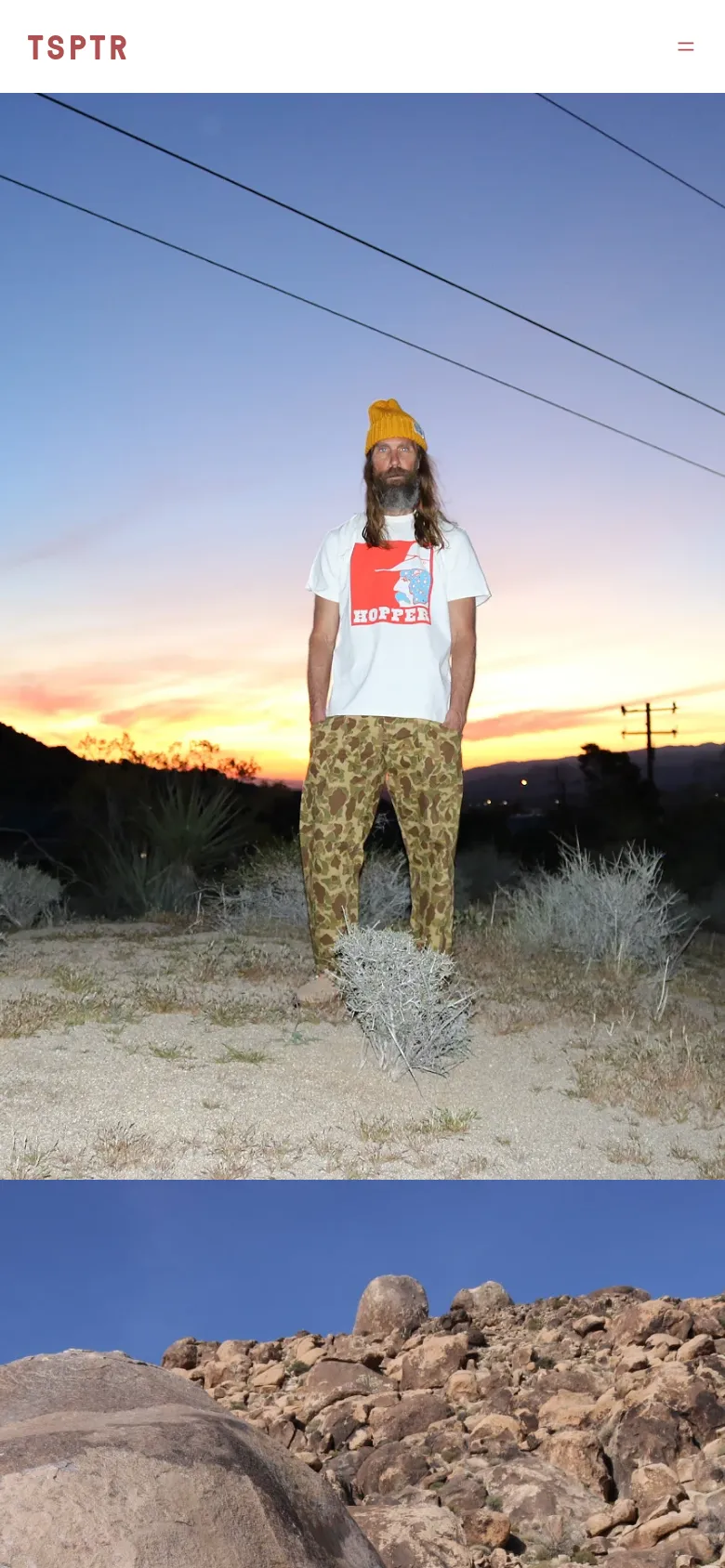 The mobile version maintains the minimalist aesthetic with a simplified header featuring the 'TSPTR' logo and a hamburger menu icon on the right. The hero image of the man in the desert is scaled to fit the vertical screen, emphasizing the sunset colors and the landscape. The layout is streamlined for vertical scrolling, focusing on large-scale imagery.
