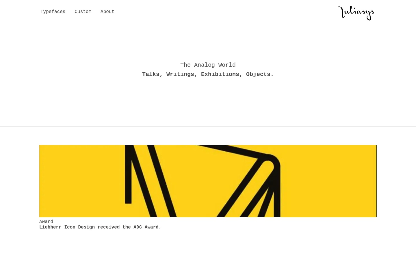 The desktop version features a minimalist white background with a top navigation menu containing 'Typefaces', 'Custom', and 'About' alongside the 'juliasys' logo. The hero section displays the headline 'The Analog World' and the subheadline 'Talks, Writings, Exhibitions, Objects.' in a monospaced font, followed by a large yellow rectangular card showcasing an icon and text about an ADC Award.