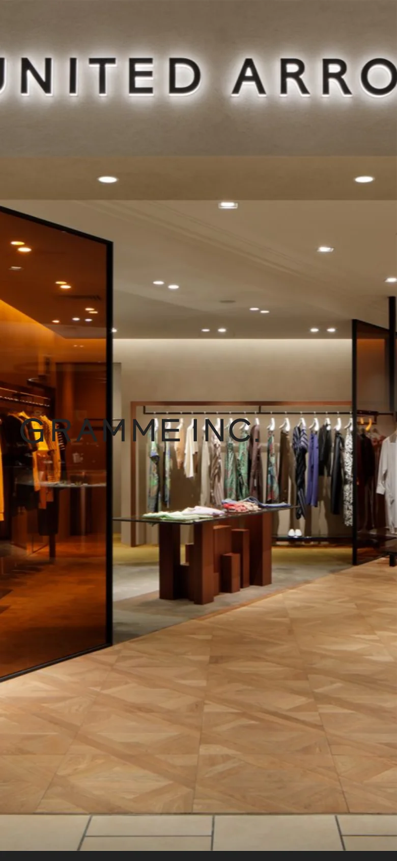 The mobile version presents a full-screen, vertically oriented view of the retail interior photograph. The 'GRAMME INC.' branding and navigation menu are overlaid directly onto the image, creating a minimalist, immersive visual experience.