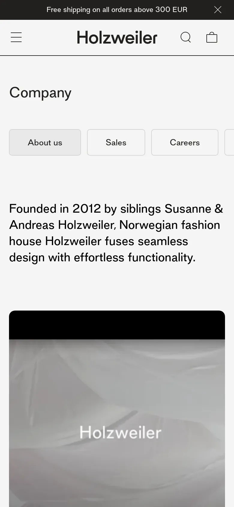 The mobile version simplifies the layout with a hamburger menu and a centered 'Holzweiler' logo at the top. The 'Company' headline and navigation buttons are stacked vertically for easier scrolling. The brand description text is centered, and the large lifestyle image occupies the bottom half of the screen.