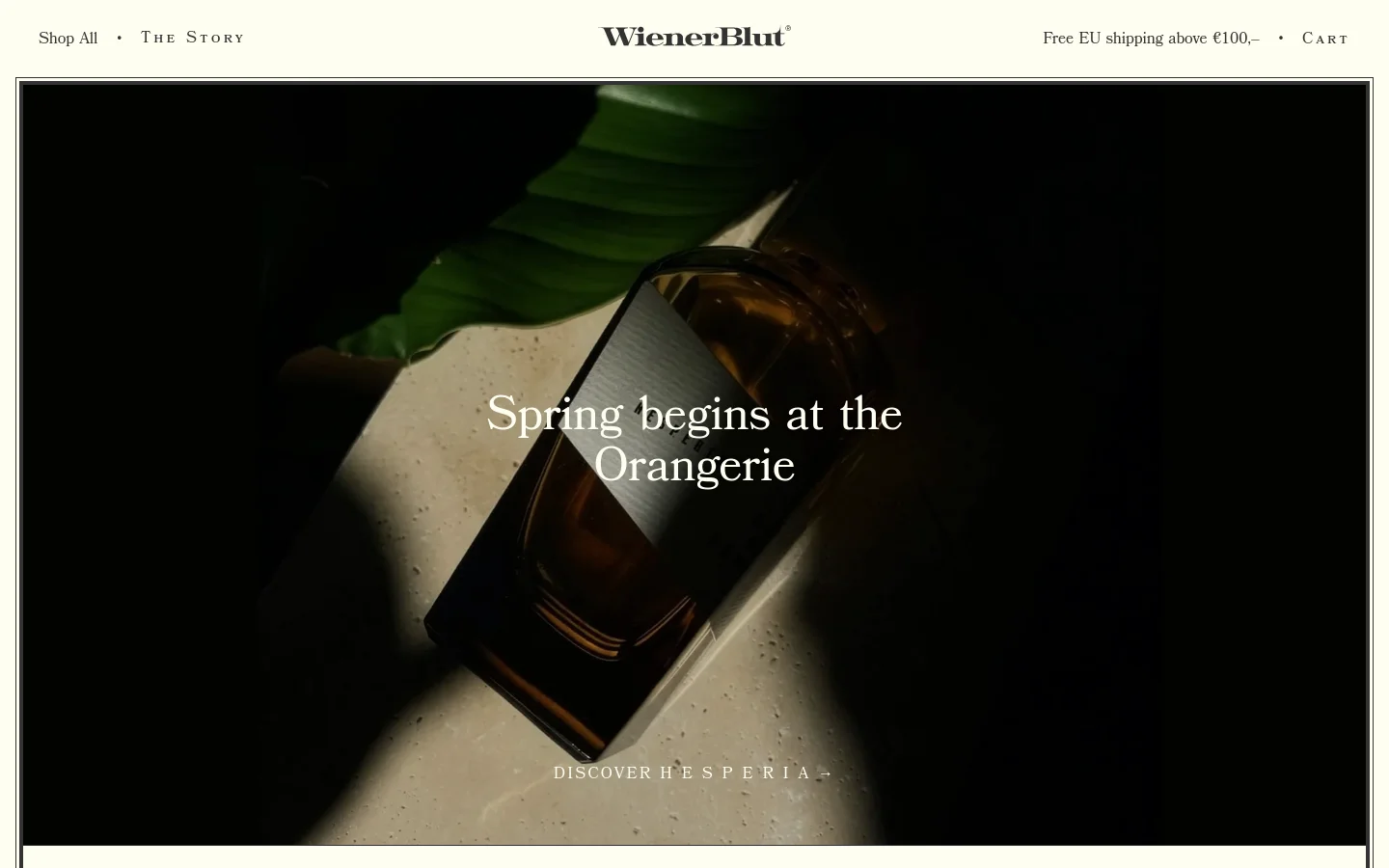 The desktop homepage features a minimalist design with a dark, moody hero image of a perfume bottle amidst green leaves and dramatic lighting. A large headline reads 'Spring begins at the Orangerie' with a 'Discover Hesperia' call to action below. The navigation bar at the top is white with black text, including links for 'Shop All', 'THE STORY', and 'CART'.