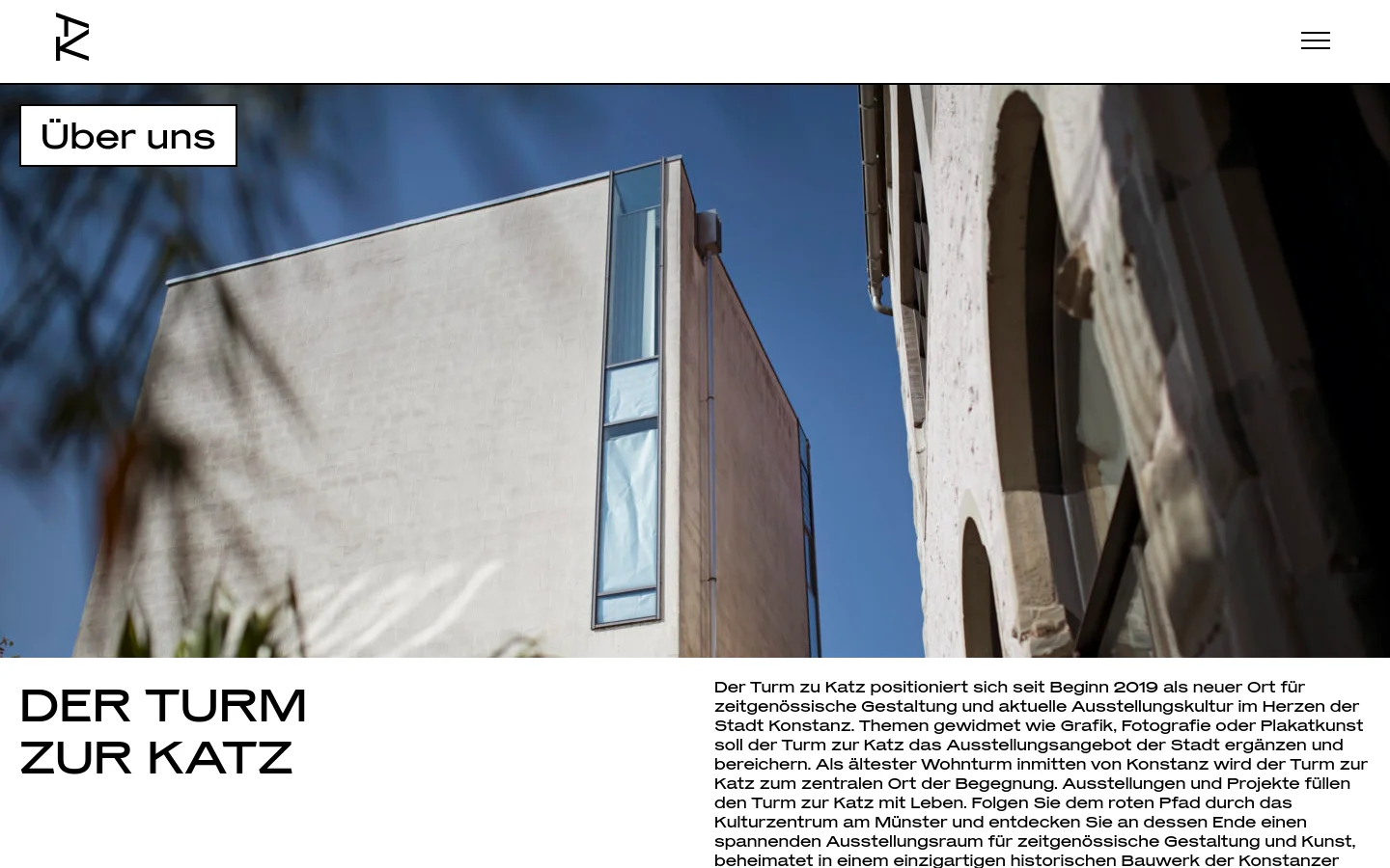 The desktop version features a large hero image of a modern architectural building against a blue sky, with a white 'Über uns' label in the top left. Below, the headline 'DER TURM ZUR KATZ' is displayed in large black capital letters on the left, with a column of descriptive German text on the right against a white background.