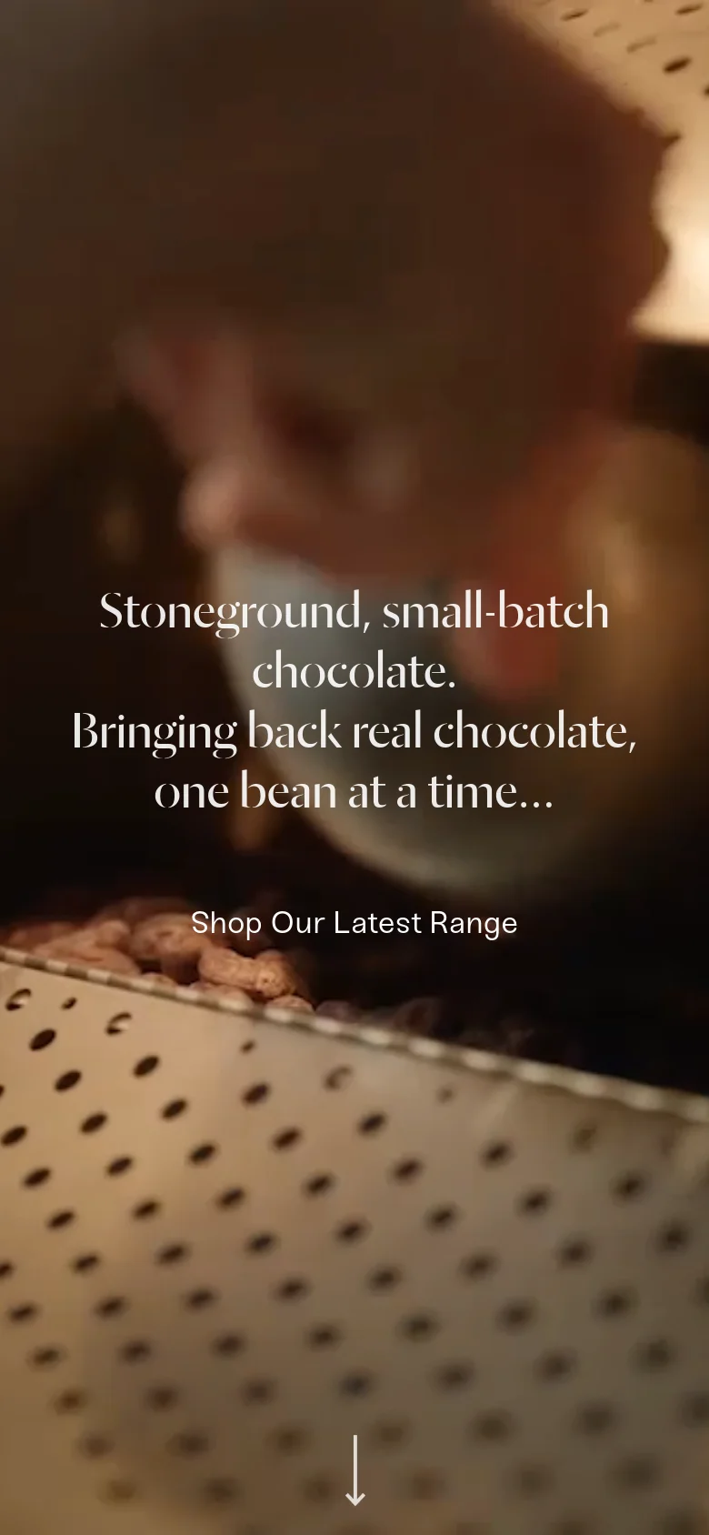The mobile version presents a vertically oriented, zoomed-in view of the chocolate processing machinery, maintaining the warm, earthy tones. The headline and 'Shop Our Latest Range' button are centered, with a white downward arrow icon at the bottom to indicate scrolling.