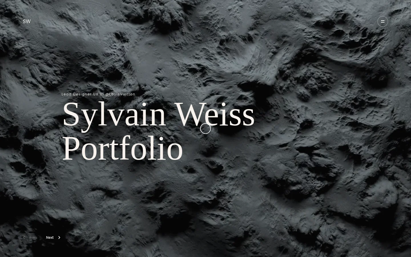 The desktop homepage features a large, dark, monochromatic textured background resembling a lunar or rocky landscape. Centered white serif text reads 'Sylvain Weiss Portfolio' with a subtitle 'Lead Designer UX UI @LouisVuitton' above it. Navigation includes 'SW' in the top left, a hamburger menu in the top right, and 'Prev' and 'Next' controls at the bottom left.
