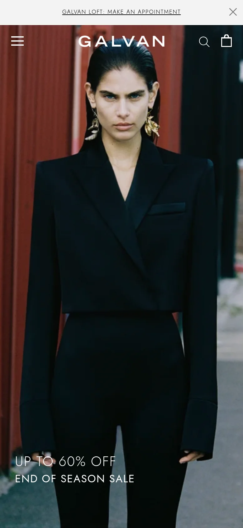 The mobile version displays a vertically oriented hero image of the same woman in a black suit, filling most of the screen. The navigation is condensed into a hamburger menu icon on the left, with a search icon and shopping bag on the right of the centered brand logo. The sale announcement text is positioned at the bottom of the image.