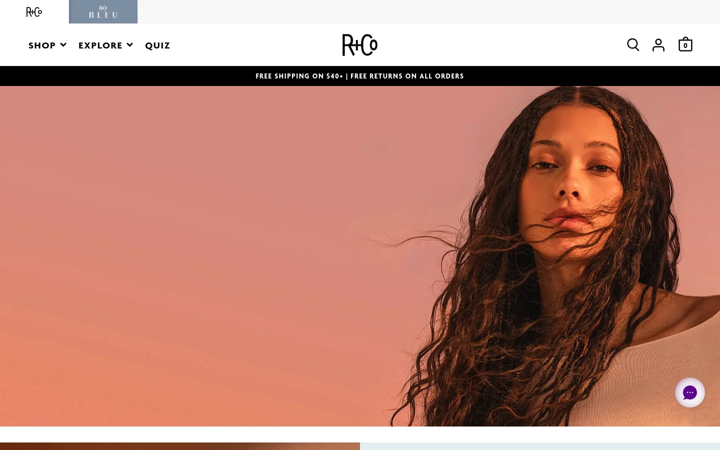 The R+Co homepage features a large hero image of a woman with long wavy hair against a pink gradient background. The navigation bar includes the R+Co logo, Shop, Explore, and Quiz links, alongside search, account, and cart icons. A black announcement bar at the top highlights free shipping and returns.