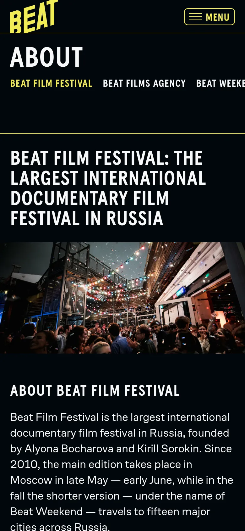 The mobile version uses a vertical layout with a black background and a hamburger menu icon labeled 'MENU' in the top right. The large 'ABOUT' heading and sub-navigation links are stacked vertically above the main hero image, which displays a crowded outdoor event at night with colorful lights.