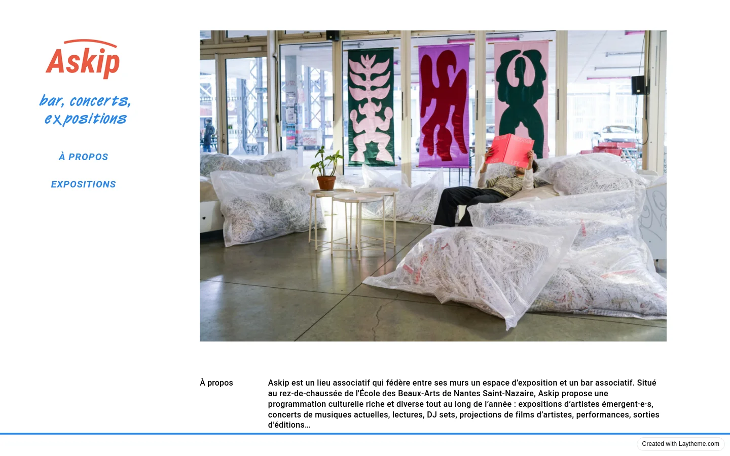 The desktop version features a split layout with a white sidebar on the left containing the red Askip logo, blue descriptive text, and navigation links. The main content area on the right displays a large horizontal photograph of a person relaxing on beanbags in a bright gallery space, followed by text sections for 'À propos', 'Newsletter', 'Contact', and 'Horaires'.