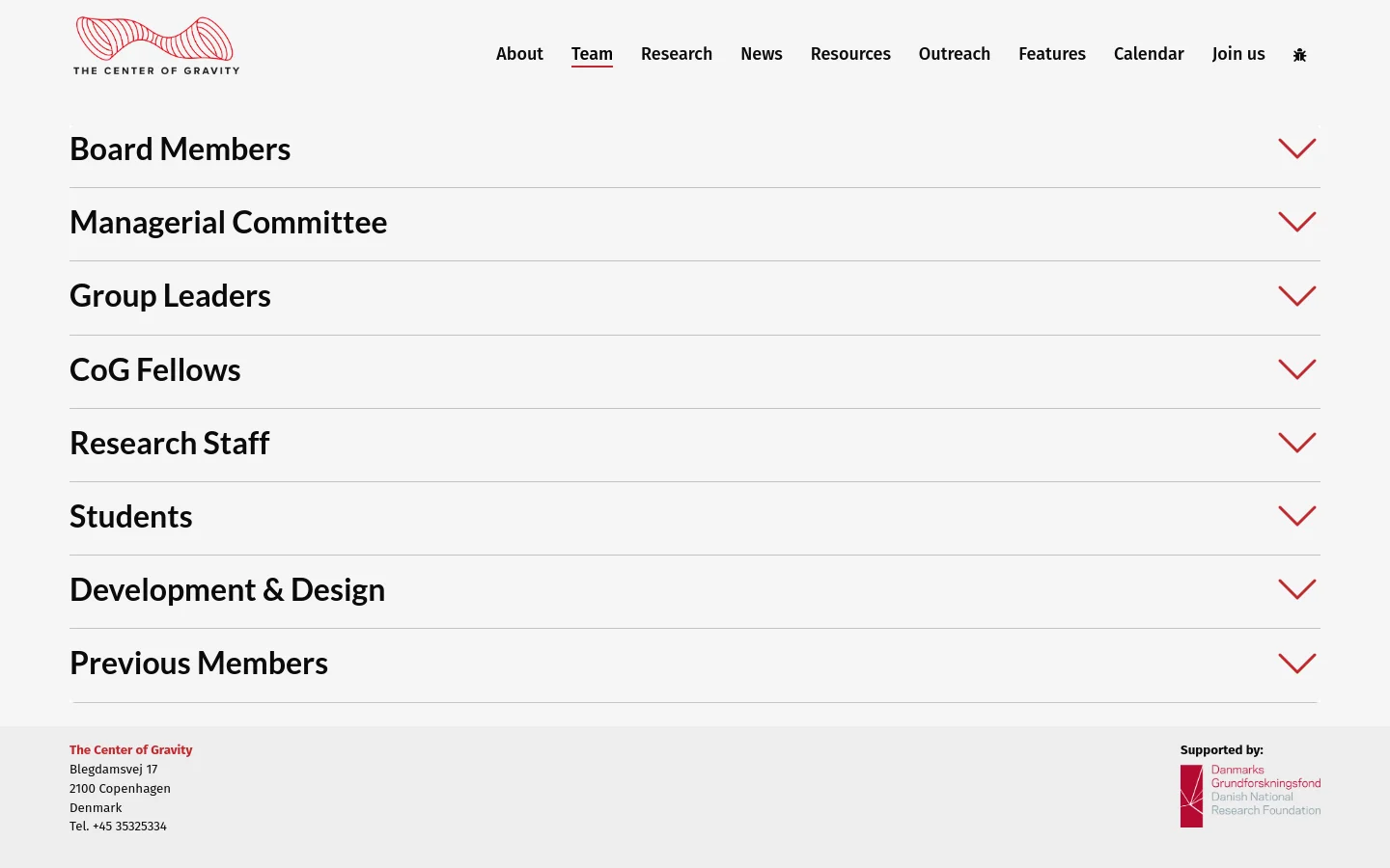 The Team page features a white background with a red logo for The Center of Gravity in the top left. A horizontal navigation menu is at the top right, followed by a series of large, black accordion-style headings for different team categories like Board Members and Group Leaders, each with a red downward arrow. The footer contains contact information and the Danmarks Grundforskningsfond logo.