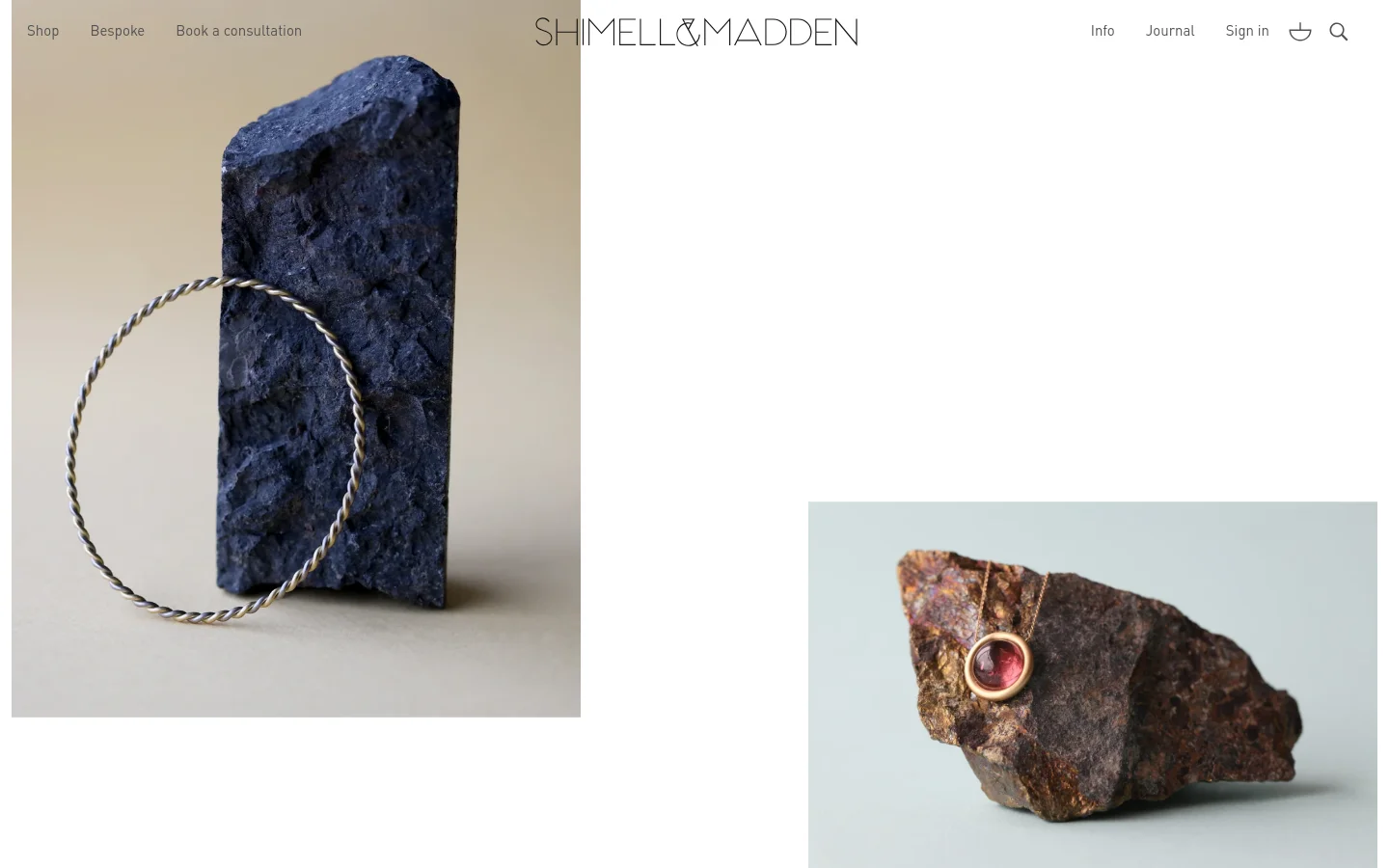 The desktop homepage features a minimalist design with a white background and elegant serif typography. A large hero image shows a silver twisted bangle resting against a dark blue stone, followed by a grid of high-quality product photography showcasing gold jewellery on natural rocks. Navigation links for Shop, Bespoke, and Book a consultation are at the top left, with the brand logo centered and utility icons on the right.
