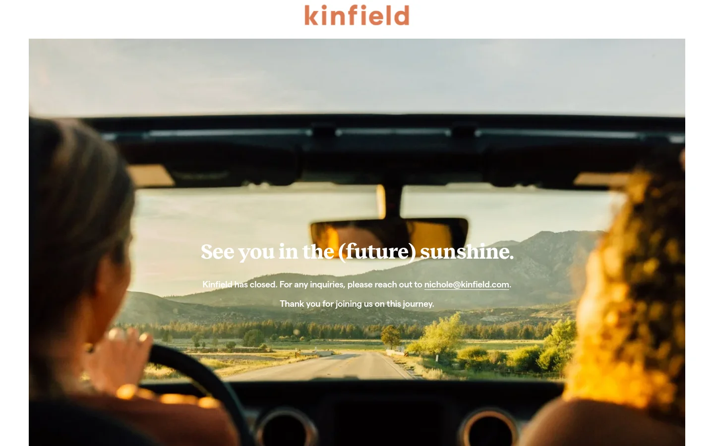 The Kinfield homepage features a large hero image showing a view from inside a vehicle looking out over a scenic landscape at sunset, with two people visible in the foreground. Centered white text reads, 'See you in the (future) sunshine,' followed by a message stating the company has closed and providing an email address for inquiries. The brand name 'kinfield' is displayed in a warm terracotta color at the top center.
