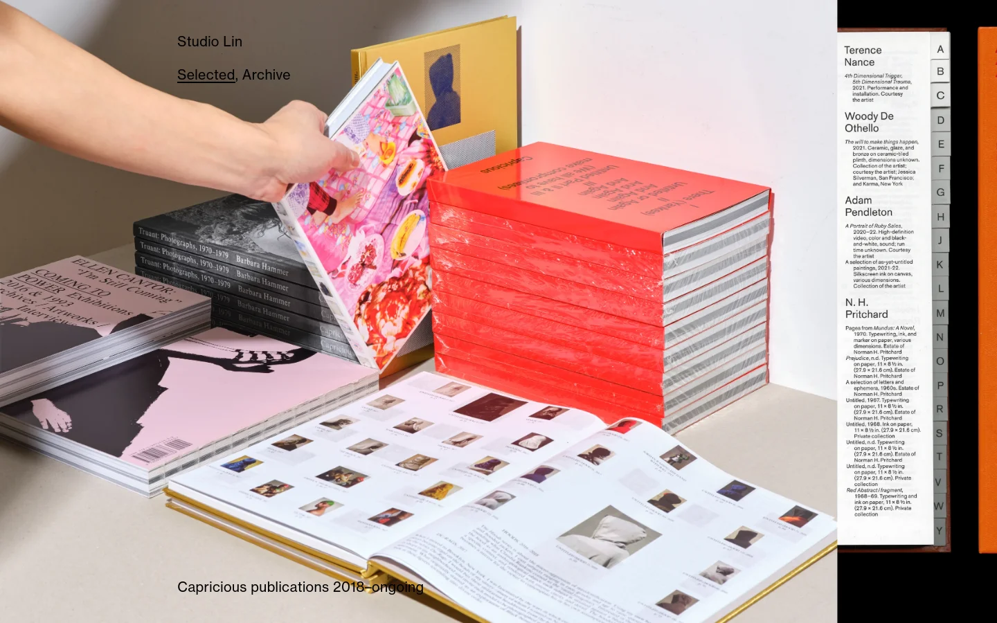 The Studio Lin homepage features a minimalist design with a large hero image of hands interacting with a stack of colorful books and publications. Navigation links for 'Selected' and 'Archive' are positioned in the upper left, and a vertical alphabetical index is on the right side. The layout is clean with a neutral background and high-quality photography.